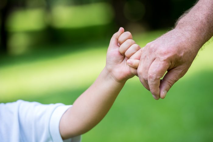 Adult holding a child's hand.